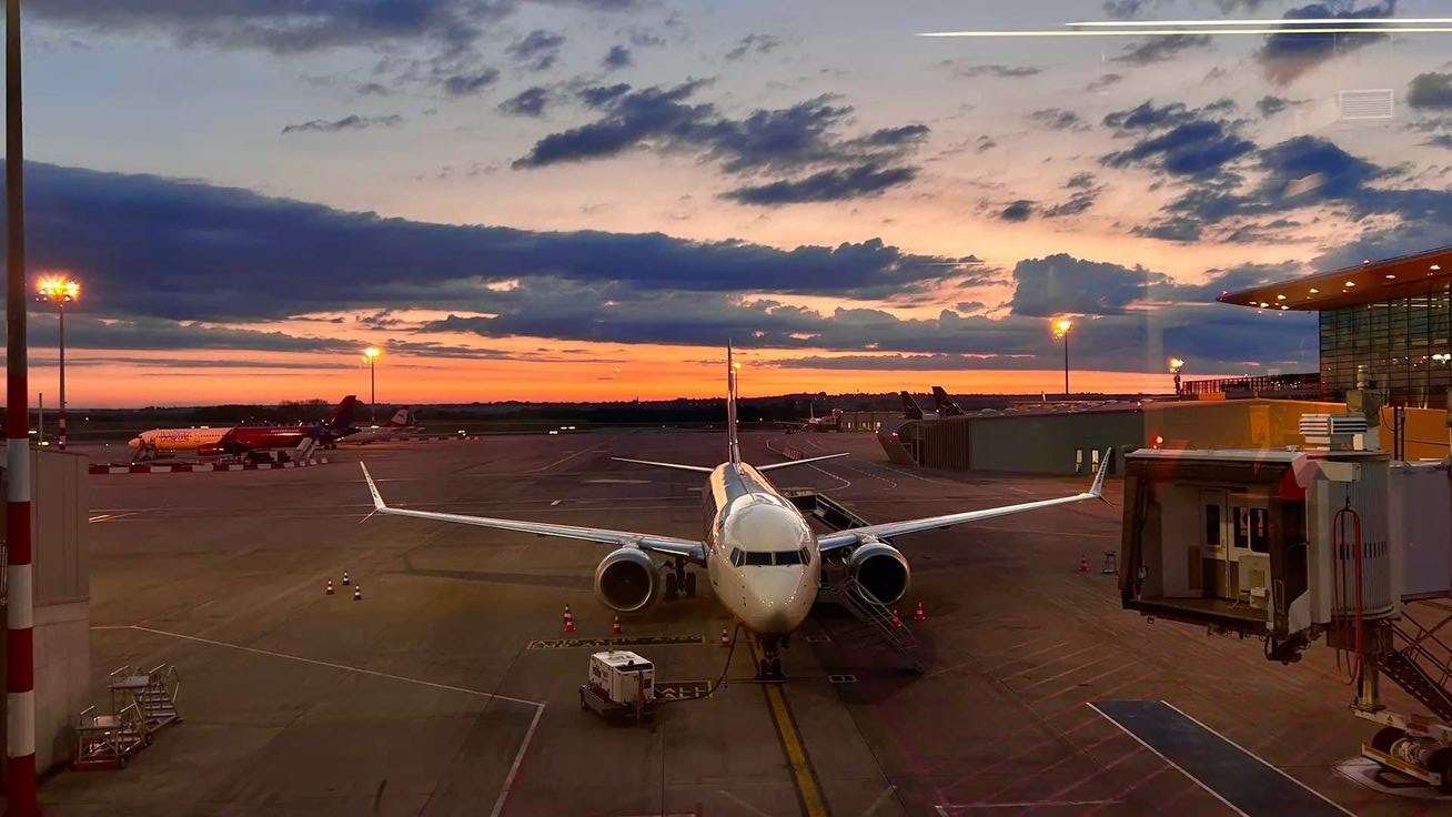 A passenger jet parked at the gate on an airport apron at sunset